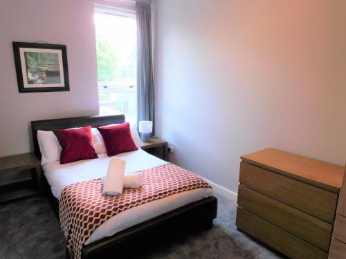 a bedroom with a bed with red pillows and a window at City Centre 2 bedroom apt, close to M8 & Tourist Attractions in Glasgow
