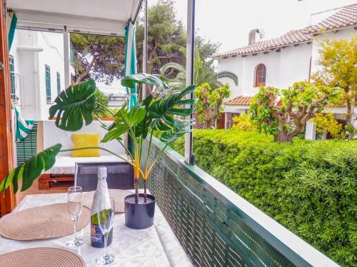 uma mesa com uma garrafa de vinho e uma planta numa varanda em Gala Apartment by Hello Homes Sitges em Sitges