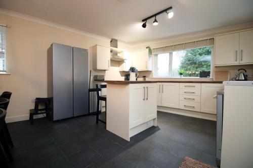 a kitchen with white cabinets and a refrigerator at Llareggub by StayStaycations in Port Talbot