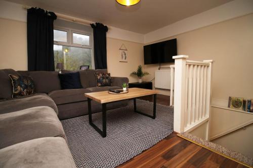 a living room with a couch and a table at Llareggub by StayStaycations in Port Talbot