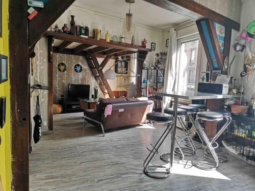 - un salon avec un canapé, une table et des tabourets dans l'établissement Atelier d’artiste proche Paris Gare nord/Stade de FR/CDG, à Stains