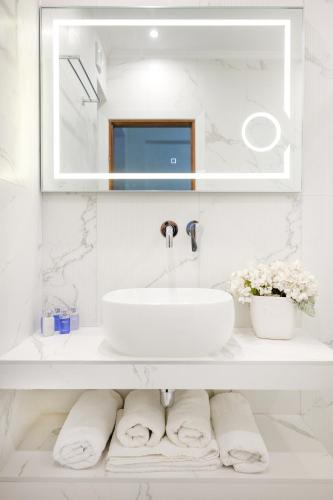 a white bathroom with a sink and a mirror at Leandros Hotel in Nea Roda