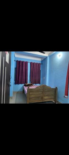 a bedroom with a wooden bed and two windows at MAA MANSHA GUEST HOUSE in Deoghar