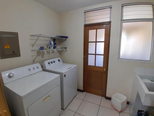 a white laundry room with a washer and a window at Comfortable Apartment with Free Parking in Guatemala