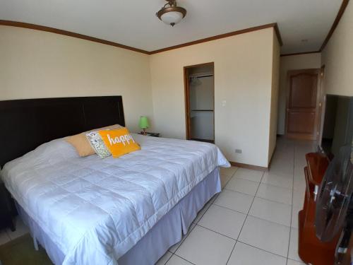 a bedroom with a bed with a orange pillow on it at Comfortable Apartment with Free Parking in Guatemala