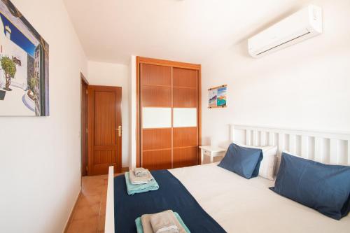 sypialnia z łóżkiem z niebieskimi poduszkami w obiekcie Villa Papagayo Lanzarote w mieście Playa Blanca
