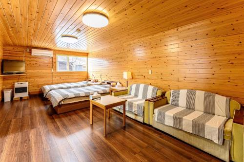 ゲストハウス風の丘 في Topetsu: سريرين في غرفة بجدران خشبية وأرضيات خشبية