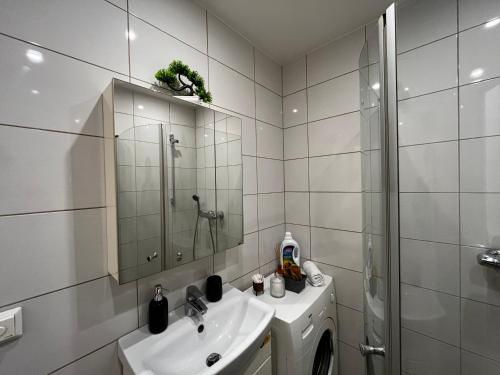 a white bathroom with a sink and a shower at Senamiesčio Studija in Kaunas