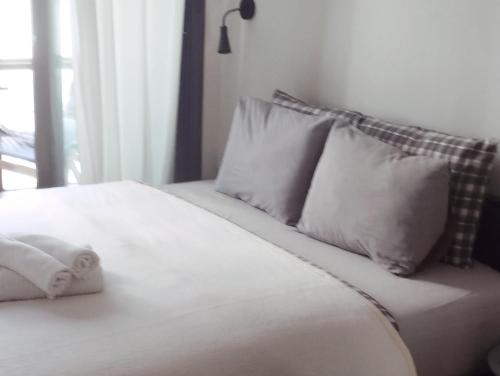 4U SuperCentral,seaside,cosy family apartment في سلانيك: سرير بمخدات بيضاء ونافذة