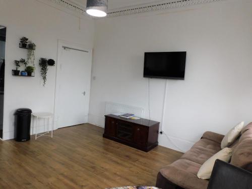 een woonkamer met een bank en een flatscreen-tv bij Comfortable 4 bed Apt in Paisley Next to Station in Paisley