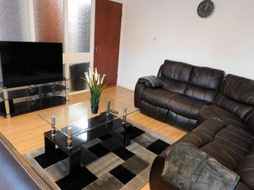 sala de estar con muebles de cuero y TV de pantalla plana en 2 bed Apt on Quiet Cul-de-Sac, Fab Location, en Paisley