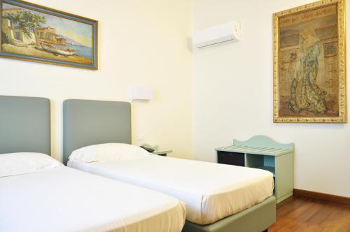 two beds in a room with a painting on the wall at Hotel San Guido in Milan