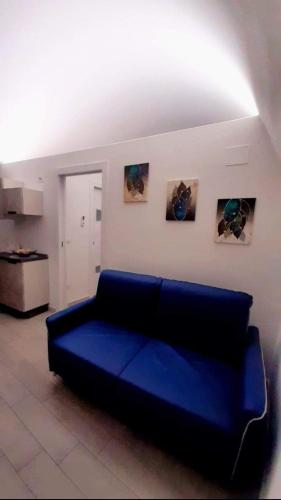 a blue couch in a living room with pictures on the wall at Casa MaLù 15 Cin I T 0 7 1 0 3 3 B 4 0 0 0 8 8 3 3 2 in Monte SantʼAngelo