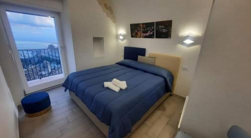 a bedroom with a blue bed and a large window at Casa MaLù 15 Cin I T 0 7 1 0 3 3 B 4 0 0 0 8 8 3 3 2 in Monte SantʼAngelo