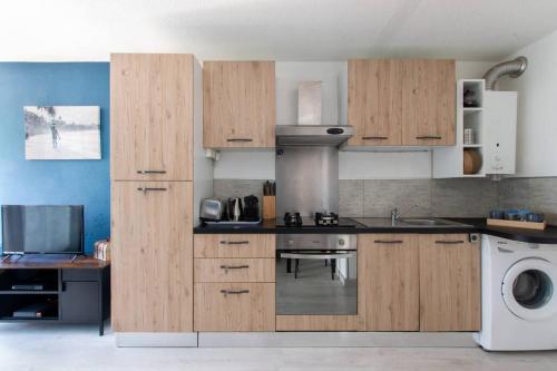 une cuisine avec des armoires en bois et un four à plaques de cuisson dans l'établissement Le bleu horizon * Terrasse * clim * Parking * wifi * Calme * Cosy, à La Grande Motte