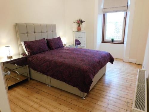 a bedroom with a bed with a purple bedspread and a window at Beautiful & spacious 2 bed apt in Glasgow West End in Glasgow