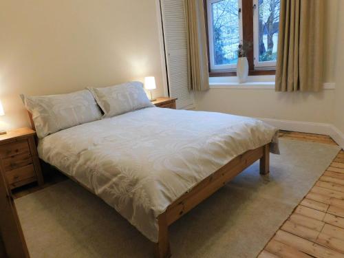 a bed in a bedroom with two night stands and a window at Beautiful & spacious 2 bed apt in Glasgow West End in Glasgow