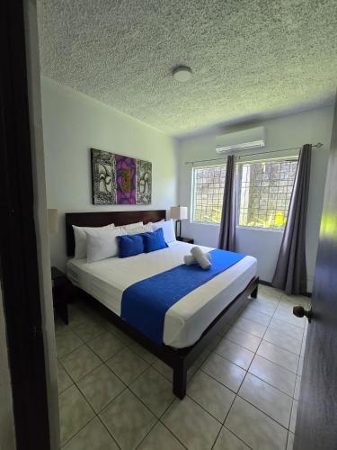 a bedroom with a large bed with blue pillows at Tropical Paradise in Jacó