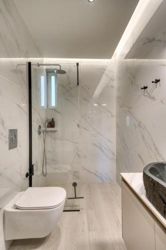 a white bathroom with a toilet and a shower at Deluxe Seaside Condo for 4 in Kandia