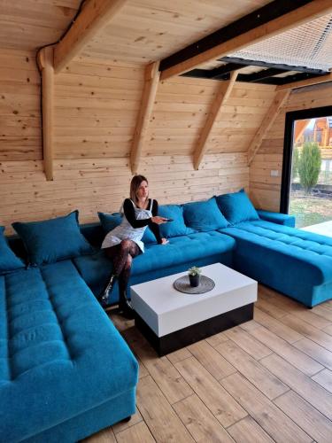 a woman sitting on a blue couch in a room at Vila Homoljska Idila1 Banja Zdrelo in Petrovac na Mlavi