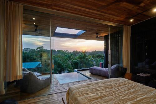 SELVA RESORT Ocean View Luxury Villas في شاطئ سانتا تيريزا: غرفة نوم بسرير ونافذة زجاجية كبيرة