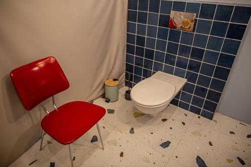 a bathroom with a toilet and a red chair at BUNNY GLAMP in Korbielów