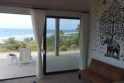 a living room with a sliding glass door with a view of the ocean at Ayampe Kachalotes, Beach house, The best view in Ayampe