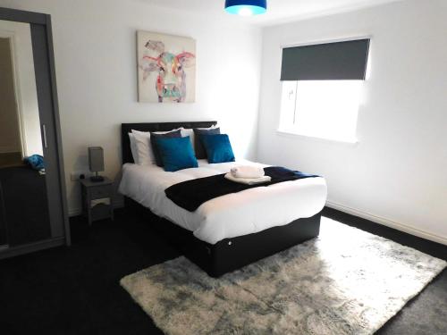 a bedroom with a bed with blue pillows and a window at Newly refurbished 2 bedroom apartment close to station and local amenities in Hamilton