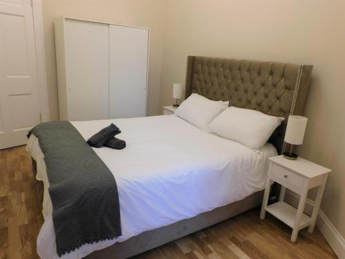 a bedroom with a large bed with a black scarf on it at Beautiful 3 bed apt in the City Centre in Glasgow