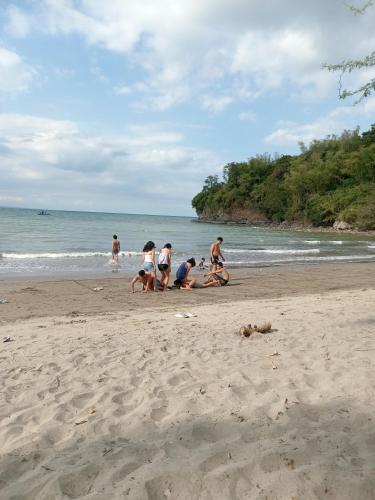 a group of people playing in the sand on the beach at De Leon Staycation at Vista de Loro in Ternate
