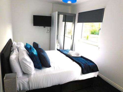 1 dormitorio con cama blanca y almohadas azules en Newly refurbished 1 bed Apt in Hamilton Close to station and local amenities en Hamilton
