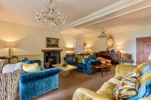 a living room with blue furniture and a chandelier at Altskeith Country House in Aberfoyle