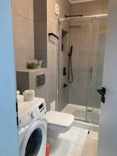 a bathroom with a shower and a washing machine at Apartamentul Max, practic și confortabil in Oradea