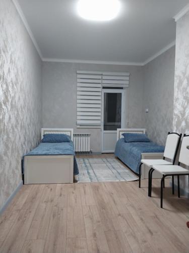 a bedroom with two beds and a table and chairs at Квартира in Shymkent