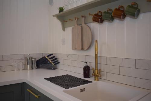 - un comptoir de cuisine avec un évier et des tasses au mur dans l'établissement Buttercup, à Rye