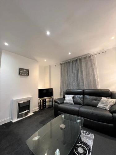 a living room with a black couch and a fireplace at Lovely 2 Bed Apt close to Silverburn Mall in Glasgow