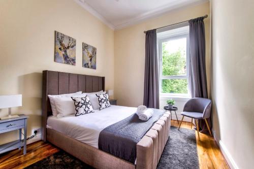 1 dormitorio con cama, ventana y silla en Stunning 5 bedroom apt, close to city centre, SEC, Hydro and motorway en Glasgow