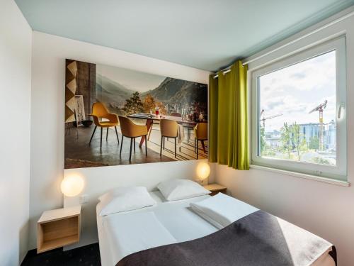 een slaapkamer met een bed en een groot raam bij B&B Hotel Weil am Rhein/Basel in Weil am Rhein