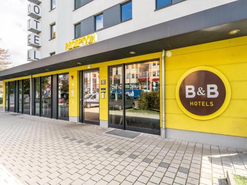 un bâtiment jaune avec un hôtel b dans l'établissement B&B Hotel Weil am Rhein/Basel, à Weil am Rhein