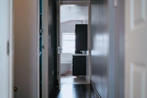 a hallway with a bathroom with a tub and a toilet at TAAY -Luxurious 3 bedroom house in South Norwood