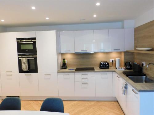 a kitchen with white cabinets and black appliances at Brand new gorgeous 2 bed Apt in Finnieston in Glasgow
