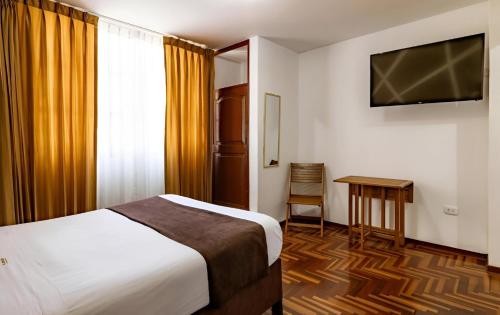 a hotel room with a bed and a table and a television at El Centurión in Trujillo