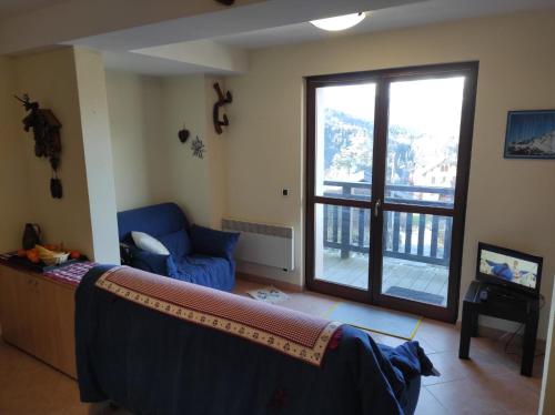 ein Wohnzimmer mit einem blauen Sofa und einem großen Fenster in der Unterkunft APPARTERMENT LE BOIS DE FEES in Saint-Gervais-les-Bains
