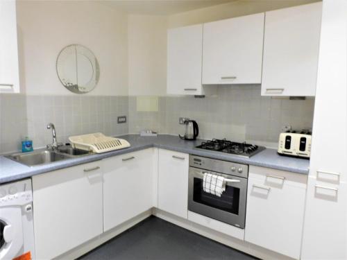 a kitchen with white cabinets and a sink and a stove at 2 Bedroom Apt in the Heart of the City Centre, perfect Location in Glasgow