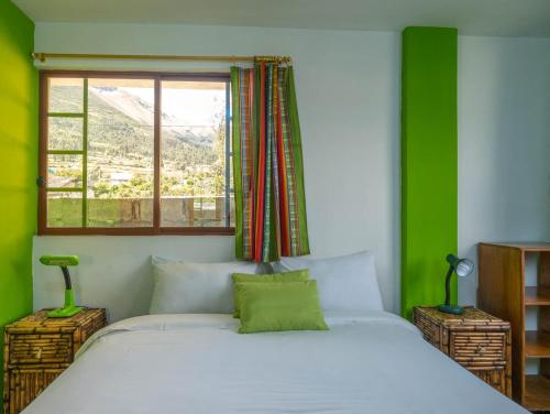 a bedroom with a large white bed with a window at Green House Araque Inn in Otavalo