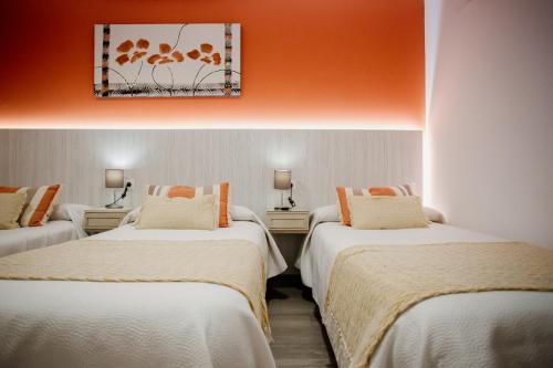 - 2 lits dans une chambre avec un mur orange dans l'établissement Pensión mastil 16. P2, à Malaga