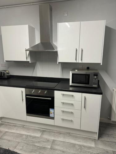 a white kitchen with a stove and a microwave at House to rent in Derby