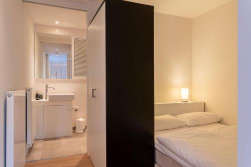 ein kleines Schlafzimmer mit einem Bett und einem Waschbecken in der Unterkunft Strandlust 21A Appartement in Wittdün