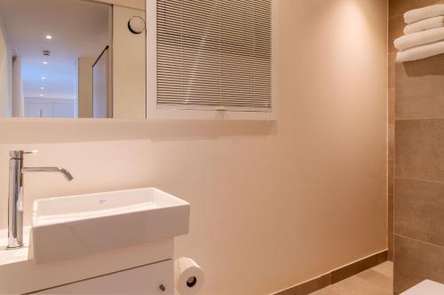 ein weißes Bad mit einem Waschbecken und einer Dusche in der Unterkunft Strandlust 21A Appartement in Wittdün
