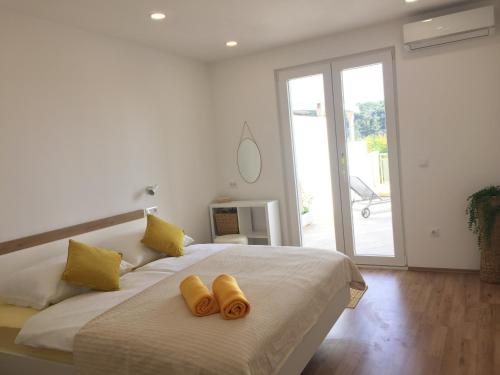 a white bedroom with a large bed with yellow pillows at Apartments Antonia in Hvar